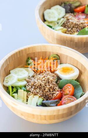 Salade de riz brun avec carotte, œuf, concombre, avocat, tomate et laitue d'agneau. Banque D'Images