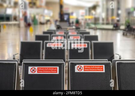 Vider les rangées de sièges dans le salon de l'aéroport pendant la pandémie du coronavirus COVID-19. Inscription d'avertissement de gros plan garder la distance, ne pas occuper adjacent Banque D'Images