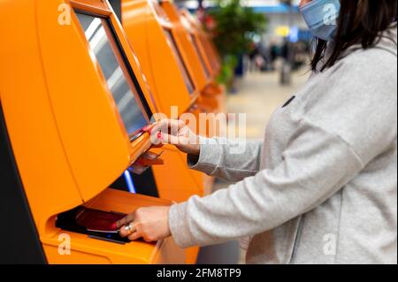 une femme scanne son passeport au comptoir de la compagnie aérienne pour s'enregistrer à l'aéroport. une femme s'auto-inscrit pour le vol. Borne de machine en libre-service Banque D'Images