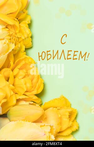 Photo verticale avec fleurs de tulipe jaunes sur fond vert Avec l'inscription en russe heureux Jubilé anniversaire Banque D'Images