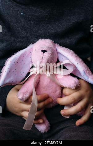 Les mains des enfants tiennent un petit jouet de lapin doux. Publicité sociale. Banque D'Images