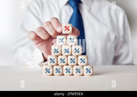 Homme d'affaires plaçant un cube en bois avec le symbole de pourcentage de contrôle ou de pourcentage sur des cubes en bois à plusieurs niveaux. Augmentation des taux d'intérêt ou de la vente à escompte co Banque D'Images