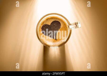 tasse à café avec enseigne en forme de coeur, vue de dessus sur fond avec lumière du soleil. Banque D'Images