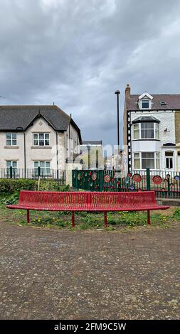 Banc métallique rouge incurvé dans les jardins publics Banque D'Images