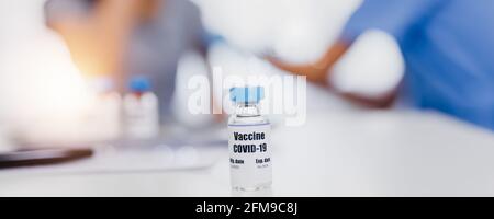 Les vaccins COVID-19 sur la table, la pandémie de coronavirus et les vaccins sauvent des millions de vies concept avec le médecin injecte les gens de fond Banque D'Images