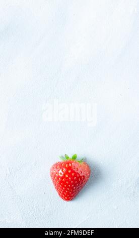 Une fraise rouge sur fond texturé gris Banque D'Images