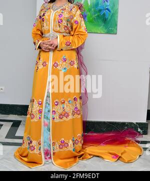 Fille marocaine portant une robe orange brodée. Le caftan est un long, fluide type de robe-comme robe qui est souvent porté au Maroc. Banque D'Images