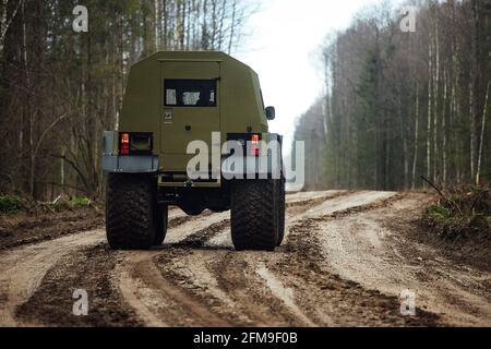 Un véhicule tout-terrain à quatre roues motrices traverse la forêt dans la boue. Un vus praticable avec de grandes roues et une grande garde au sol. Spécial transpo Banque D'Images