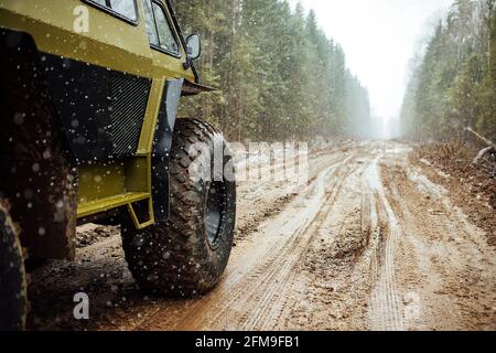 Un véhicule tout-terrain à quatre roues motrices traverse la forêt dans la boue. Un vus praticable avec de grandes roues et une grande garde au sol. Spécial transpo Banque D'Images