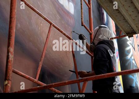 Rome, Italie. 07e mai 2021. Un artiste de rue Jorit Agoch, faisant des touches finales vues lors de la création de la murale, à l'extérieur de l'ancienne usine de viscosa de la SNIA, représentant Luana d'Orazio, une fille de 22 ans qui est décédée alors qu'elle travaillait dans une entreprise textile le 4 mai 2021.selon les dernières estimations de l'INAIL (Institut national d'assurance contre les accidents du travail), en Italie, en 2021, deux personnes meurent chaque jour dans leur travail. Crédit : SOPA Images Limited/Alamy Live News Banque D'Images