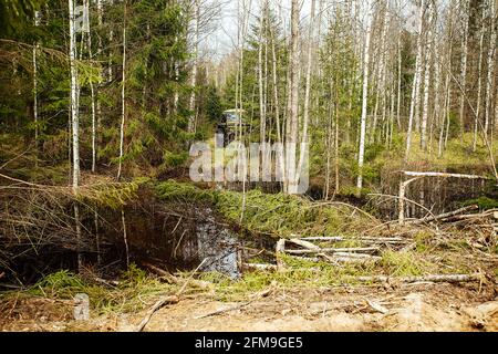 Un véhicule tout-terrain à quatre roues motrices traverse la forêt dans la boue. Un vus praticable avec de grandes roues et une grande garde au sol. Spécial transpo Banque D'Images