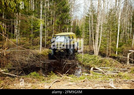 Un véhicule tout-terrain à quatre roues motrices traverse la forêt dans la boue. Un vus praticable avec de grandes roues et une grande garde au sol. Spécial transpo Banque D'Images