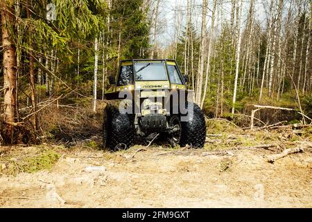 Un véhicule tout-terrain à quatre roues motrices traverse la forêt dans la boue. Un vus praticable avec de grandes roues et une grande garde au sol. Spécial transpo Banque D'Images