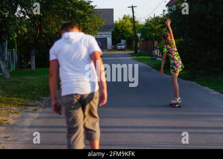 Recentrer les jeunes filles et garçons heureux jouant sur le skateboard dans la rue. Elle a mis les bras vers le haut. Les enfants de race blanche à la planche de Penny, à la pratique du skateboard. Réfrigérateur Banque D'Images