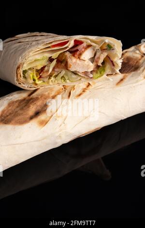 Classique shawarma kebab pita avec poulet et légumes et sauce sur fond noir. Dans la section Banque D'Images