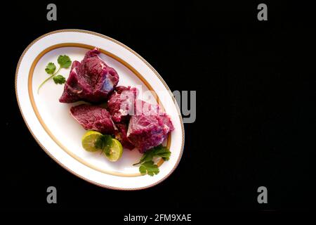 Steaks de bœuf frais décorés de légumes et d'herbes sur une assiette blanche, sélective. Banque D'Images