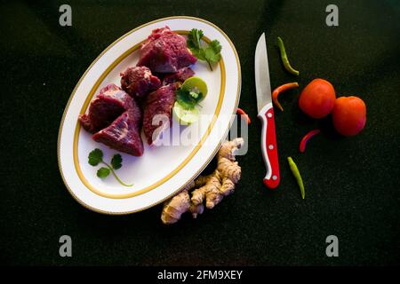 Steaks de bœuf frais décorés de légumes et d'herbes sur une assiette blanche, sélective. Banque D'Images