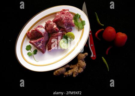 Steaks de bœuf frais décorés de légumes et d'herbes sur une assiette blanche, sélective. Banque D'Images