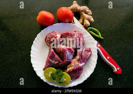 Steaks de bœuf frais décorés de légumes et d'herbes sur une assiette blanche, sélective. Banque D'Images