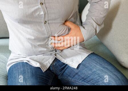 un homme dans une chemise qui ressent de la douleur pour une douleur estomac autour de l'annexe Banque D'Images