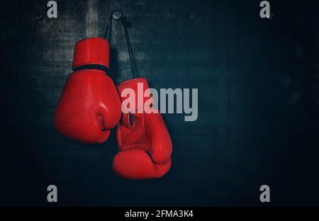 Close up paire de gants de boxe en cuir rouge suspendue au-dessus de mur noir with copy space Banque D'Images