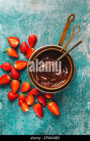 Une casserole de chocolat fondu et de morceaux de fraise à côté. Vue de dessus, espace vide Banque D'Images