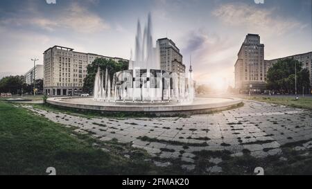 Coucher de soleil derrière la fontaine de la Strausberger Platz de Berlin et la tour de télévision. Banque D'Images