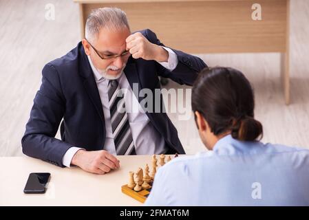 Deux employés masculins jouant aux échecs sur le lieu de travail Banque D'Images