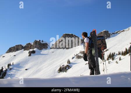 Homme avec le fût de bière Mittenwald sur son dos, skis de randonnée, équipement devant la crête du sommet du Rotwandkopf (1, 858 m) Rotwand (1, 884 m) dans les montagnes de Mangfall, Spitzingsee, haute-Bavière, Bavière, Allemagne, Banque D'Images