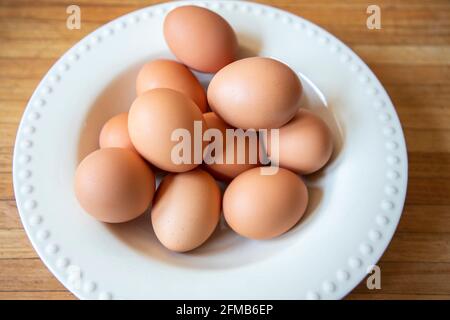 Œufs bruns biologiques dans un bol blanc assis sur une table en bois. Banque D'Images