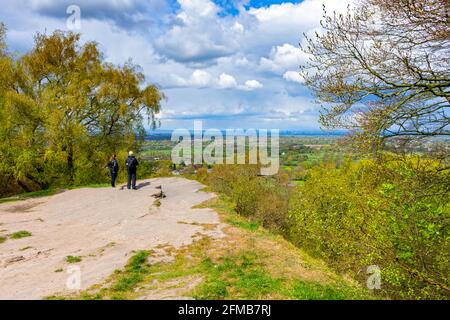 Un couple qui surplombe la plaine de Cheshire jusqu'aux tours lointaines du centre-ville de Manchester. Depuis Alderley Edge, Cheshire, Angleterre, Royaume-Uni. Banque D'Images