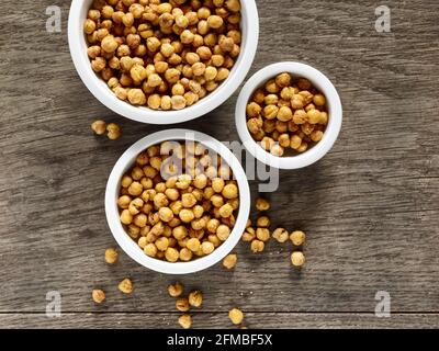 Cuisine ayurvédique - pois chiches rôtis au four dans des bols en porcelaine de divers dimensions sur une plaque en bois Banque D'Images