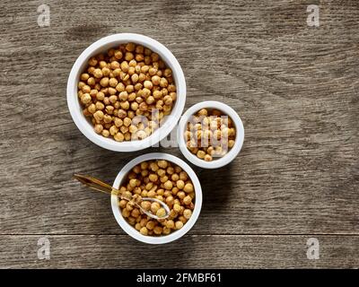 Cuisine ayurvédique - pois chiches rôtis au four dans des bols en porcelaine de divers dimensions sur une plaque en bois Banque D'Images