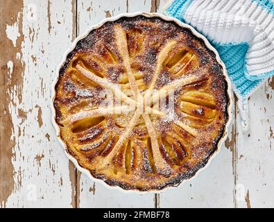 Vue de dessus d'une tarte aux pommes « Alsatian-Art » cuite dans un moule à tarte bleu clair avec crochetés bleu clair et blanc porte-pots Banque D'Images