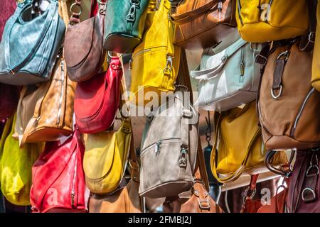 De nombreux sacs à main en cuir coloré couleurs vives accrochées sur l'exposition dans le marché de rue commerçante à Florence, Florence, Toscane, Italie Banque D'Images