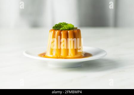 Pudding à la vanille. Dessert sucré avec garniture caramel sur table blanche. Banque D'Images