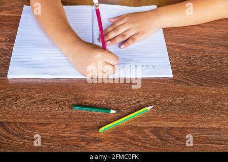 La main de l'élève est écrite sur papier sur la table de l'école. Banque D'Images