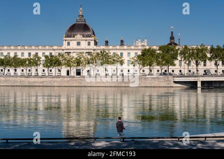 Lyon (France), 03 mai 2021. Vue sur l'Hôtel Dieu et la Basilique de Fourvière avec un pêcheur au premier plan sur les rives du Rhône. Banque D'Images