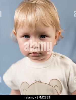 Portrait en gros plan d'une fille blonde âgée de 1 an. Le regard sérieux d'un enfant aux yeux bleus Banque D'Images