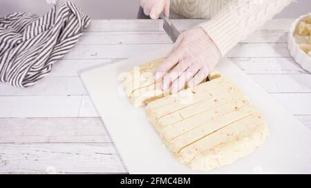 Étape par étape. Coupe de fudge de canne à sucre fait maison sur un tableau de découpe blanc. Banque D'Images