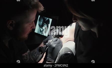 Homme faisant tatouage noir pour femme en studio Banque D'Images