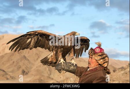 Bayan Ulgii, Mongolie, 2 octobre 2015 : homme avec son cheval et aigle d'or de l'Altaï au coucher du soleil Banque D'Images