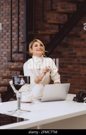 Le concept de blogging et de vlogging est une jeune femme blogger parlant à la caméra. Mise au point sélective douce, flou artistique, bruit de flou artistique. Banque D'Images