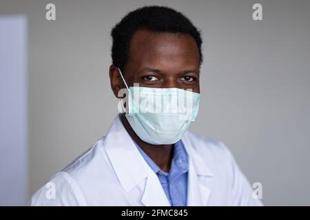 Jeune homme noir portant un manteau blanc et un masque Banque D'Images