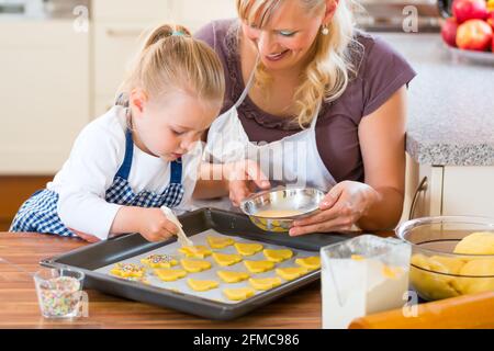 La cuisson avec la famille - Mère et fille coat self made cookies à l'aide d'un pinceau Banque D'Images