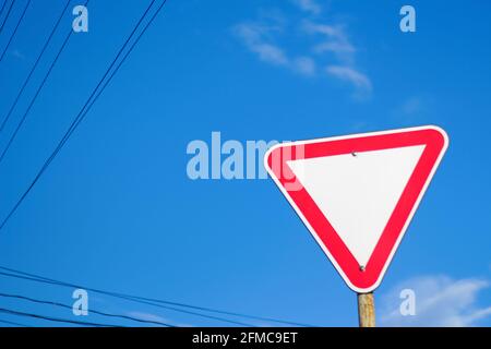 Flou artistique vierge triangle vide rouge avertissement route signe avec fond bleu ciel. Direction du danger. Hors foyer. Banque D'Images