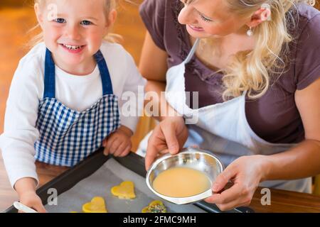 La cuisson avec la famille - Mère et fille coat self made cookies à l'aide d'un pinceau Banque D'Images