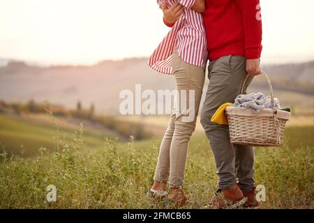 Un jeune couple dans un câlin sur un pré tout en allant pique-niquer sur une belle journée ensoleillée. Relation, amour, ensemble, pique-nique, nature Banque D'Images