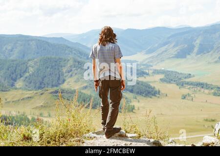 L'homme regarde autour de la colline. Guy se dresse au sommet de la montagne et jouit d'une vue panoramique sur la vallée de Kootenay, Creston, Colombie-Britannique, Canada Banque D'Images