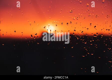 Gouttes d'eau de pluie sur la fenêtre contre le ciel du soir. Gouttes de pluie sur le verre, coucher de soleil, image liée à la météo Banque D'Images